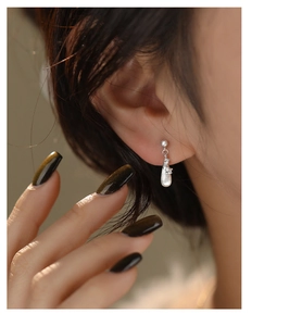 Macro detail of brushed silver teardrop earrings featuring small cubic zirconia stones