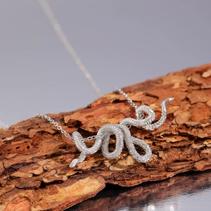 Punk style silver snake pendant necklace displayed on a textured tree bark background