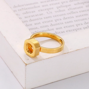 Minimalist gold stainless steel hexagonal ring displayed on a white decorative frame