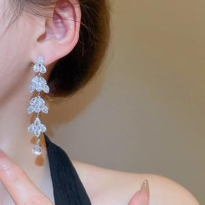Close-up of sparkling leaf tassel earrings with silver finish on a female model