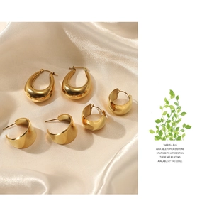 Detailed view of various geometric 14K gold plated earrings on premium beige silk fabric