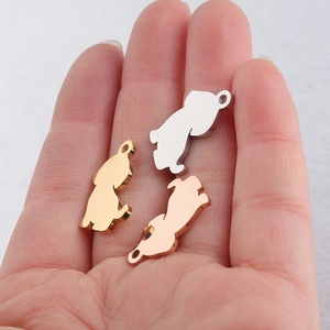 Three dog-shaped stainless steel charms in silver, gold, and rose gold on a palm