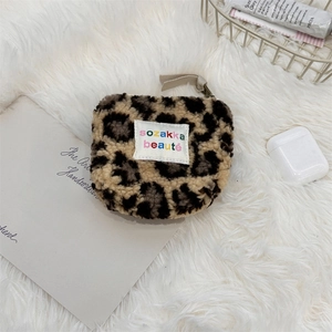 Detailed close-up of leopard print plush pouch with zip closure on white rug