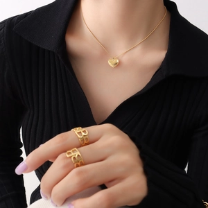 Golden heart pendant necklace and镂空 B-letter rings set on black knit background