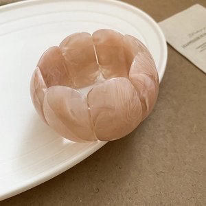 Detailed texture of pink marble resin acrylic bangle on a minimalist white ceramic plate