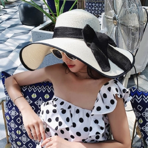 Close-up of a wide brim straw hat featuring a stylish black bow for sun protection