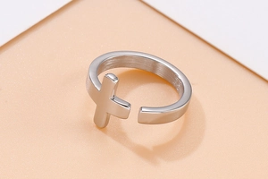 Close-up of polished stainless steel silver cross open ring detail on warm background