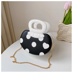 Detail of black and white heart pattern handbag with elegant gold chain strap
