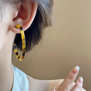 Close-up of vintage resin C-shaped hoop earrings with brown leopard pattern on model