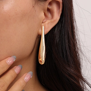 Macro close-up of shiny gold teardrop earrings showing smooth polished metallic texture