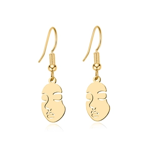 Detailed close-up of golden hollow abstract face earrings with sleek metallic finish