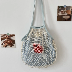 Detail der hellblauen Netz-Schultertasche mit rotem Herzaufnäher und weißem Gewebe