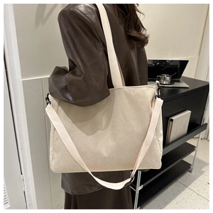 Detailed texture of beige corduroy tote bag worn by a model in casual office setting