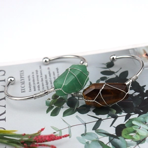 Detail of silver wire wrapped natural green and brown crystals on open cuff bracelets