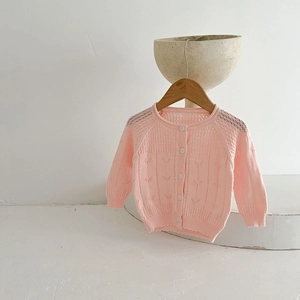 Détail gilet tricot rose bébé fille, cardigan ajouré doux et respirant pour petite enfance.