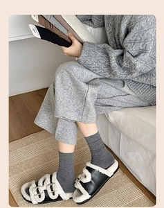 Detail of grey knitted mid-calf cotton socks paired with stylish faux fur slide sandals