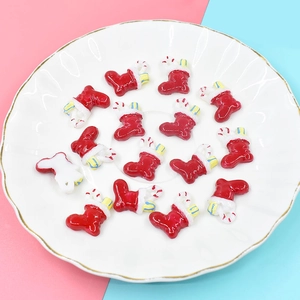 Flat lay of 14 red resin Christmas stocking charms in a white plate for DIY crafts
