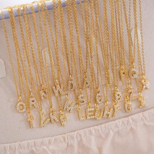 Close-up of gold square letter pendants with zircons displayed in a jewelry box