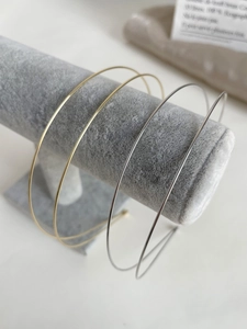 Detail of minimalist gold and silver thin metal headbands on a velvet display stand