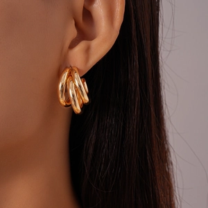 Close-up of a gold triple-interlocked C-shaped earring worn on a model's ear