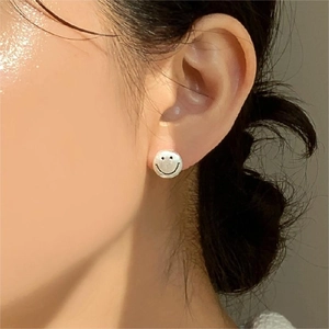 Close-up of minimalist 925 sterling silver smiley face stud earrings worn by a model