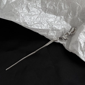 Detail view of a silver liquid metal hair pin with minimalist wavy design and reflective finish