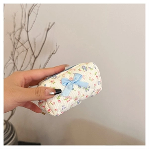 Close-up of white floral cotton mini makeup pouch with blue ribbon bow detail