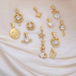 Nahaufnahme verschiedener 24K vergoldeter Edelstahlanhänger mit CZ-Einlagen auf Seide