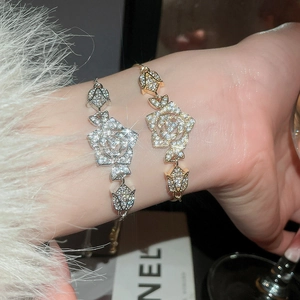 Macro detail of elegant sparkling zircon rose flower bracelets in silver and gold plating