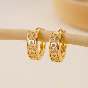 Detail of gold zircon earrings with heart-shaped hollow patterns hanging on a branch