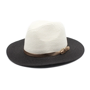Detail of two-tone woven straw panama hat with elegant gold buckle and black wide brim