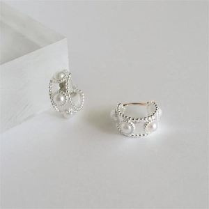 Close-up of 925 sterling silver C-shaped hoop earrings with pearls and milgrain texture