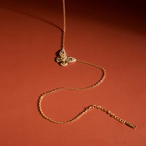 Vue détaillée d'un collier en or 18 carats avec un pendentif papillon serti de cristaux