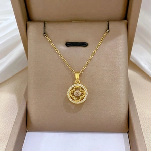 Elegant gold clover pendant necklace with sparkling diamonds on a silk jewelry box cushion