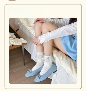 Detail of white lace ruffle crew socks featuring a blue bow and ballet flat shoes