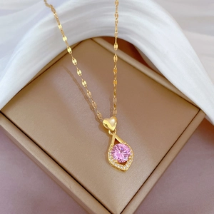 Détail macro du collier coeur doré avec pierre rose dans un écrin à bijoux de luxe