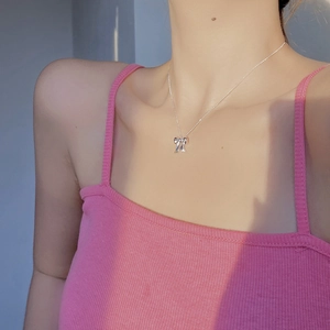 Dettaglio della collana con ciondolo a fiocco d'argento indossata sulla clavicola