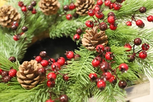 Detailed view of artificial green pine needles with red berries and brown pine cones