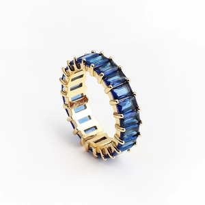 Détail d'une bague dorée ornée de pierres de zircone cubique bleues rectangulaires