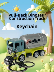 Detail of a green dinosaur pull-back mixer truck keychain with metallic bell and keyring