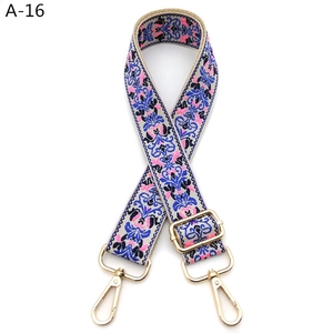 Close-up of ethnic floral embroidery strap with gold metal hooks and adjustable buckle