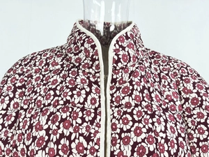 Detail of quilted stand collar jacket featuring purple floral print and white piping edge