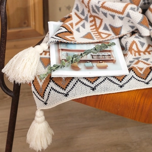 Detail of bohemian knit throw with geometric patterns and tassels on a wooden chair