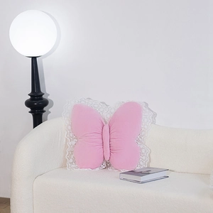 Detail of pink butterfly plush pillow with white lace trim on a white sofa cushion