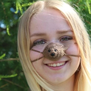 Detail of a brown hand-knitted bear nose warmer with thick yarn and secure side straps
