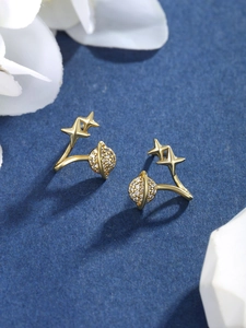 Detail shot of gold star and planet earrings with sparkling zircon on a blue backdrop