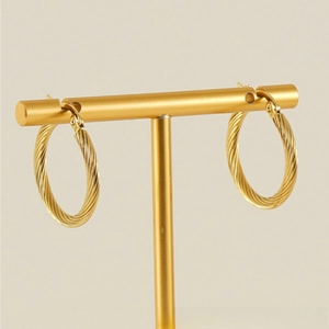 Macro shot of gold-plated twisted hoop earrings with a metallic spiral design