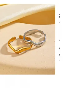 Detailed view of wave-shaped open rings in polished gold and silver finishes