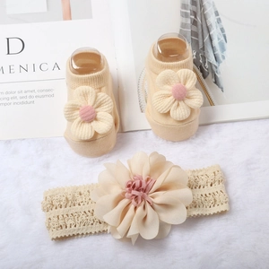 Dettaglio del set fascia in pizzo beige e calzini con delicati fiori rosa applicati