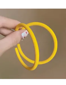 Detail view of large matte yellow acrylic hoop earrings held between fingers
